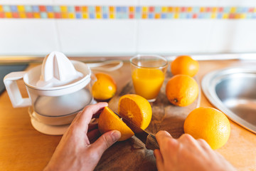 Point of View of of Man Cutting Oranges with Knife and Using Electric Squeezer.