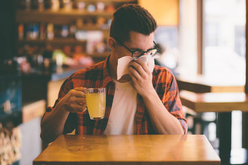 sick student blowing his nose into a tissue