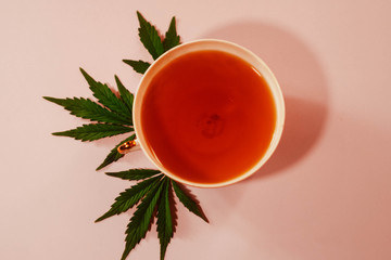 Cannabis tea with leafs. Sedative and relaxing effect. Anxiety treatment. Pink background. Flat lay. Copy space. Medical marijuana. 