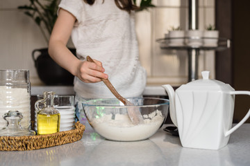 A preschool girl prepares homemade plasticine from flour, salt and sunflower oil and blue food coloring. The child prepares the dough. Homemade plastiline. Plasticine. play dough. 