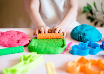 Child hands playing with colorful clay. Homemade plastiline. Plasticine. play dough. Girl molding modeling clay. Homemade clay.