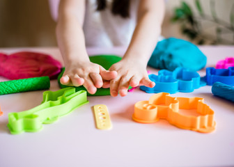 Child hands playing with colorful clay. Homemade plastiline. Plasticine. play dough. Girl molding modeling clay. Homemade clay.