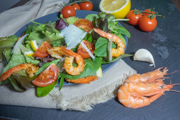 Grilled shrimps, vegetables and herbs salad on a plate