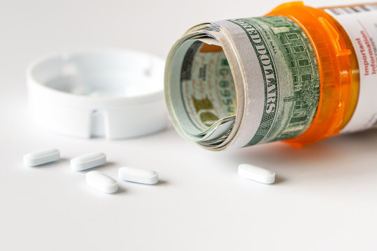 Healthcare cost concept using US Dollars with white medicine pills spilling from medicine bottle. - Powered by Adobe