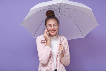 Close up of portrait of happy Caucasian woman holding white umbrella, having pleasant conversation...