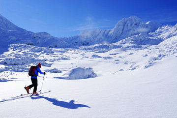 Fototapeta na wymiar Ski touring in harsh winter conditions. Ski tourer sporting in in the mountains. Winter alpine landscape