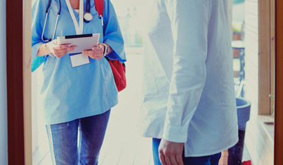 Female doctor with clipboard during home visit while entering house
