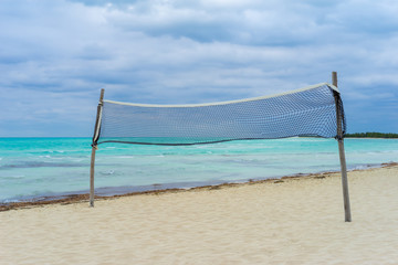 Vacation in Cuba. Beach volleyball net on a background of white sand and emerald water. Panorama of a deserted beach on the Caribbean sea. Vacation in the Caribbean. Visit To Liberty Island.