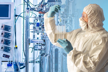 A man in protective clothing with test tubes in his hands against the background of a laboratory...