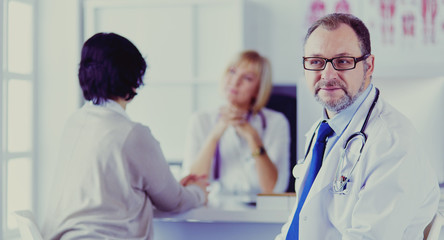 Fototapeta premium Portrait of senior doctor in office sitting at the desk