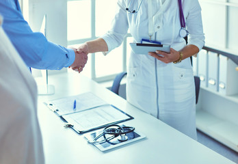 Woman doctor handshaking with a senior couple