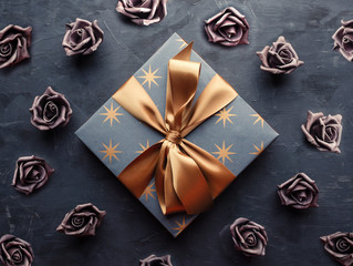 Blue gift box with gold ribbon bow on blue background. Overhead shot.