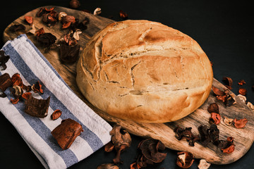 Homemade freshly baked bread over a wooden table with a cloth and floral decoration. Closeup.