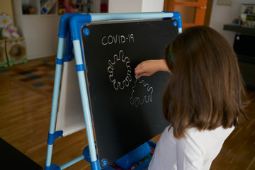 girl draws a virus on the blackboard at home. coronavirus concept