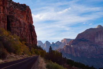 A two lane road hugs the towering red rock cliff on the way up to Zion's tunnel.