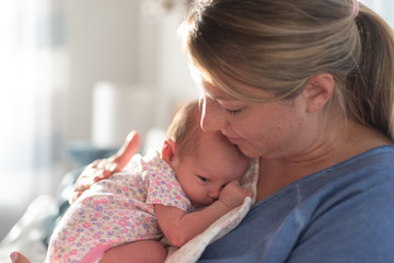 Young mom holding newborn daughter on chest