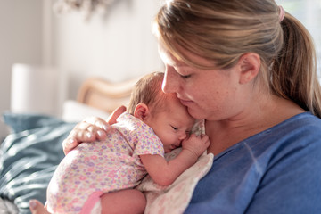 Young mom patting baby girl's back for burp after breastfeeding