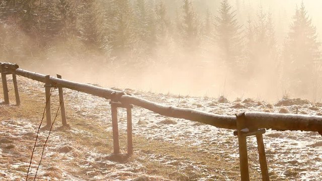 Rural scene near the Zakopane town in Poland. Wooden timbered fence on foggy spring morning. Mist flows between firs.