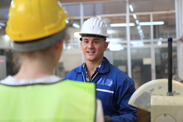 Male and Female Industrial Engineers in Hard Hats Discuss New Project while Using Laptop. They Work in a Heavy Industry Manufacturing Factory.