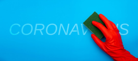 concept image of hand in red rubber protecting glove holding sponge with green fiber cleaning...