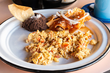 Desayuno de huevos revueltos a la mexicana con frijoles negros y chilaquiles