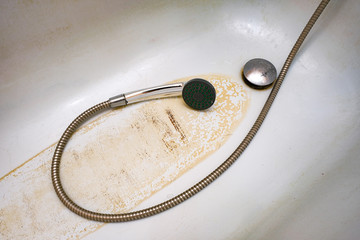 Extremely dirty bath drain mesh, hole and surface covered with limescale or lime scale and rust, cleaning calcified and rusty bathroom equipment