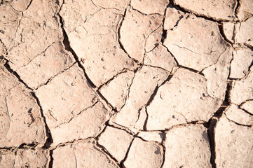 Full frame background of dry cracked light red colored earth