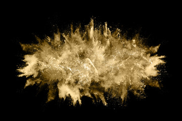 Golden powder explosion on black background. Freeze motion.