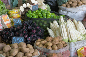 Corn, purple corn, potatoes, lime and cassava displayed with prices at a local grocery