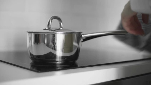 Woman takes off saucepan from induction cooker