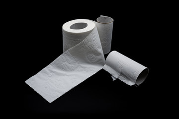 Eine angebrochene Rolle Toilettenpapier und zwei leere Papphülsen auf schwarzem Hintergrund freigestellt 