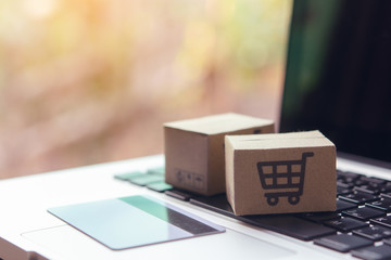 Online shopping - Paper cartons or parcel with a shopping cart logo and credit card on a laptop keyboard. Shopping service on The online web and offers home delivery.