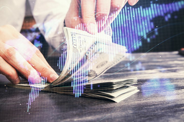 Multi exposure of financial theme drawing hologram and USA dollars bills and man hands. Business...