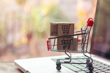 Shopping online concept - Parcel or Paper cartons with a shopping cart logo in a trolley on a...