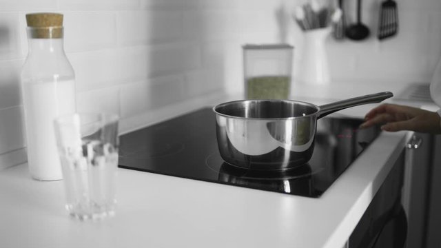 Close up of woman puts a pot and turned on induction cooker