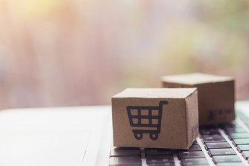 Online shopping - Paper cartons or parcel with a shopping cart logo on a laptop keyboard. Shopping service on The online web and offers home delivery.