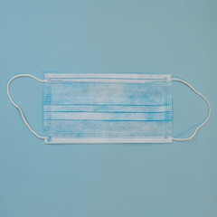 Surgical Ear-Loop mask. Protective medical mask on blue background. Framed in square. Coronovirus, quarantine, epidemic, pandemic, cold,illness. Medicine concept and health