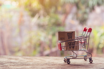 Shopping online concept - Parcel or Paper cartons with a shopping cart logo in a trolley on wood...