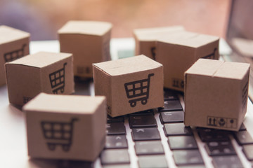 Online shopping - Paper cartons or parcel with a shopping cart logo on a laptop keyboard. Shopping service on The online web and offers home delivery.