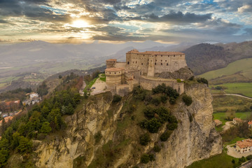 Fototapeta na wymiar Aerial view of San Leo town and fortress used once as a prison on a rocky outcrop near the Adriatic sea resort Rimini and San Marino with Roman church