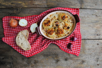 Stuffed Onions in Ceramic Baking Pan on a wooden rustic background. Top view.