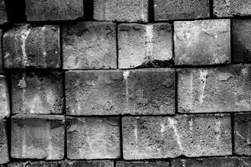 bricks randomly piled by a wall in black and white