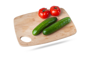  fresh vegetables cucumbers and tomatoes lie on a kitchen wooden cutting board. isolate on white background