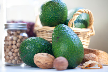 Avocado as main objects, with decorative objects in fore and background such as nuts and a bottle of beans. Kitchen setup.