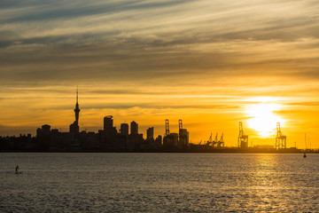 ニュージーランド　オークランドの桟橋からの夕日でオレンジ色に染まった空とスカイタワー
