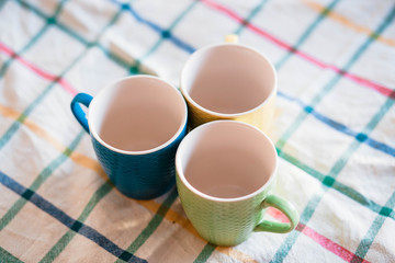 Cups. Colored cups lying side by side and lying on a towel. Blurred background. The sun is shining on the cup.
