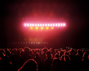 Crowd of fans facing a stage full of red lights at night time