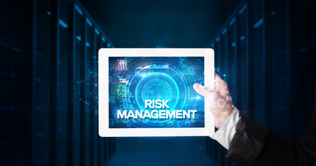 Young business person working on tablet and shows the inscription: RISK MANAGEMENT, business concept