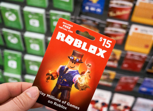 Roblox Gift Card In A Hand Over Gift Cards Background Stock Photo Adobe Stock - roblox gift card singapore