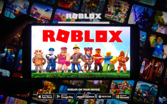 Roblox logo and app on a mobile screen in a hand.